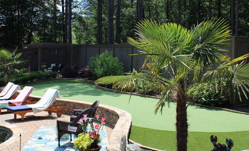 Backyard putting green with lounge chairs and tree